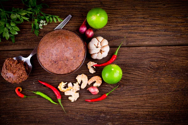Kahverengi ahşap arka planda organik karides ezmesi (kapi) ve Tayland malzemesi. Üst Görünüm