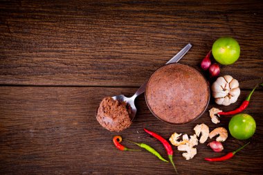 Ahşap zemin üzerinde cam kase içinde karides ezmesi (kapi) ve thai malzemesinin üst görünümü.