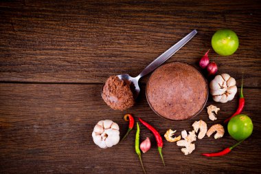 Ahşap zemin üzerinde cam kase içinde karides ezmesi (kapi) ve thai malzemesinin üst görünümü.