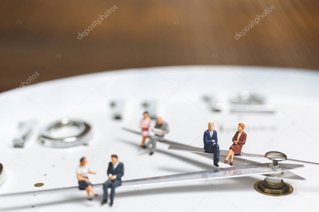 Miniature people Businessman sitting on clock , Concept of Time and Work