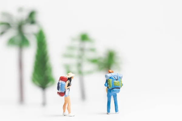 Miniatyr personer: resenären med ryggsäck promenader på vit bakgrund — Stockfoto
