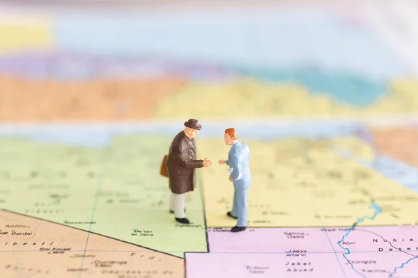 Miniature people : Tourist handshake on world  map background ,  Journey and travel Concept