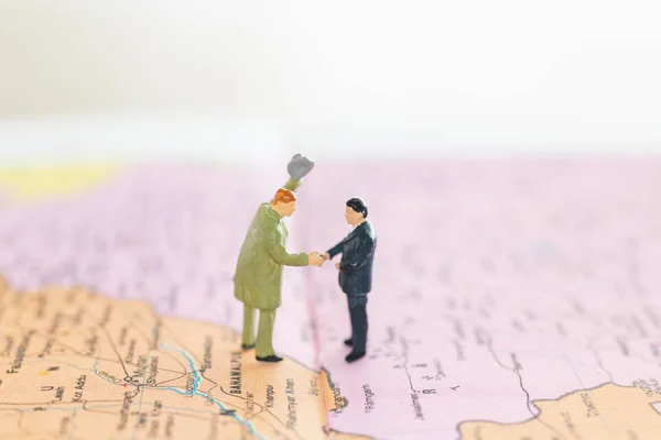 Miniature people : Tourist handshake on world  map background ,  Journey and travel Concept