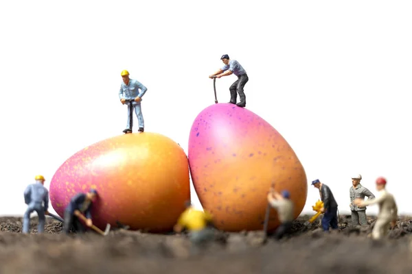 Miniature people work at Easter-eggs for Easter day with white background