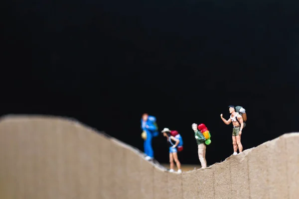 Miniaturmenschen: Reisende mit Rucksack auf dem Papierberg — Stockfoto