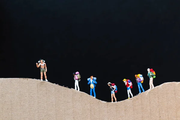 Miniaturmenschen: Reisende mit Rucksack auf dem Papierberg — Stockfoto
