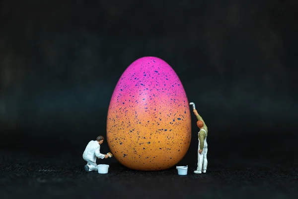 Miniature people  painting Easter-eggs for Easter day