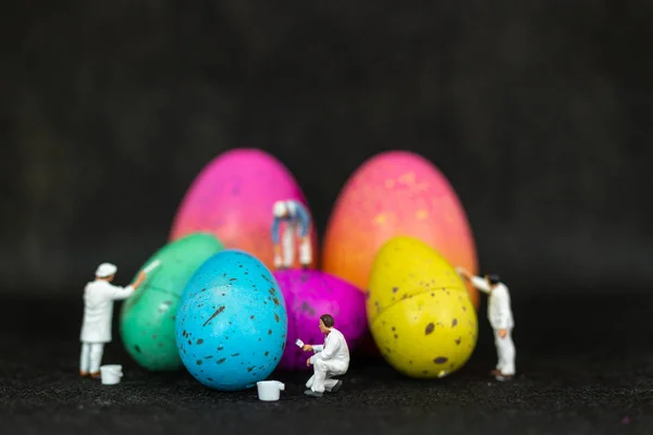 Miniature people  painting Easter-eggs for Easter day