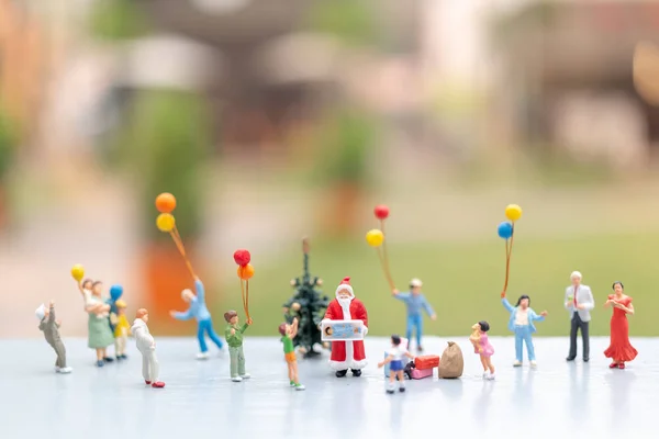 Pessoas em miniatura: Papai Noel segurando presente para a família feliz — Fotografia de Stock