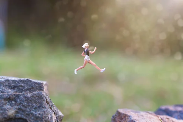 ミニチュアの人々:自然の背景を持つ岩の崖の上を走る — ストック写真