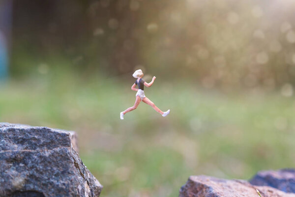 Miniature people : Running on rock cliff with nature background 