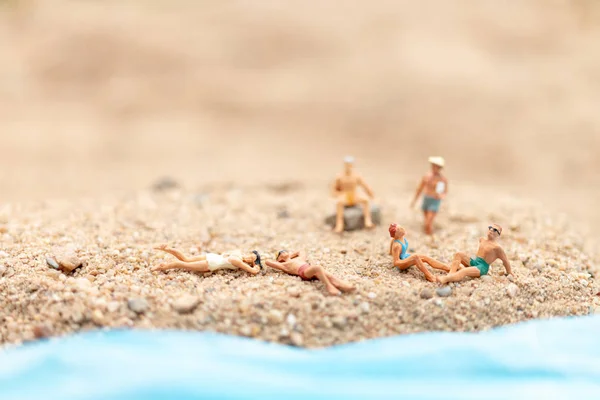 Personas en miniatura con traje de baño relajándose en la playa — Foto de Stock