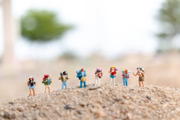 ミニチュアの人々:砂の上を歩くバックパックを持つ旅行者 — ストック写真