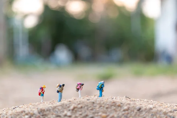 Miniatyr människor: resenär med ryggsäck gå på sand — Stockfoto