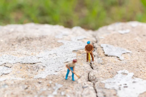 Miniatyr människor: arbetarteam arbetar på betong med sprucken — Stockfoto