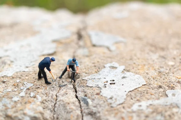 Miniature people : Worker team working on  concrete with cracked