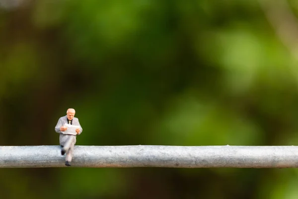 Pessoas em miniatura: pessoas de negócios sentadas em um fio — Fotografia de Stock