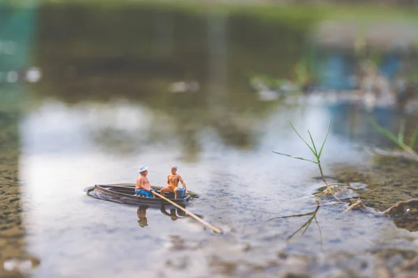 Миниатюрные рыбаки ловят рыбу на лодке — стоковое фото