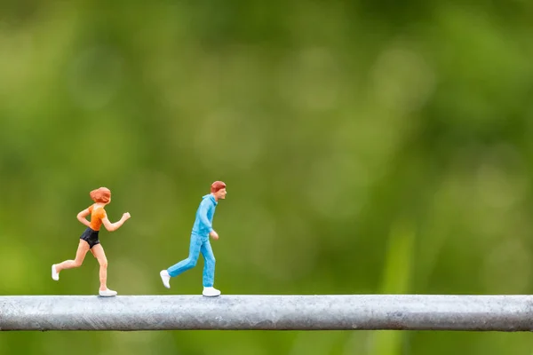 Miniatuur mensen: jonge mensen die op een draad lopen — Stockfoto