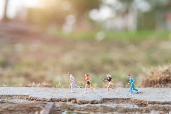Personas en miniatura: Correr en la carretera con fondo natural —  Fotos de Stock