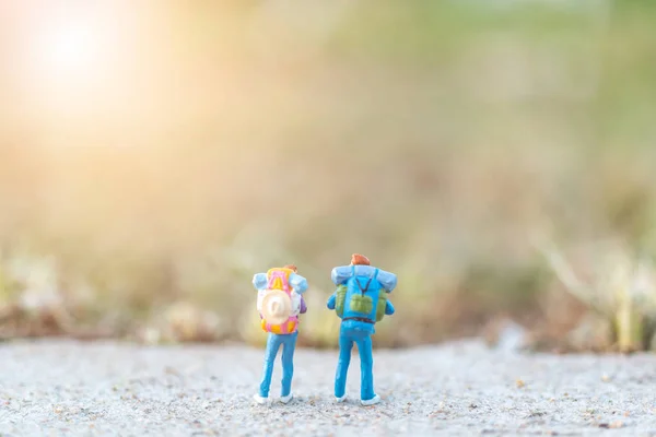 Reizigers miniatuur met rugzak staande op de weg — Stockfoto