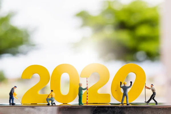 Pessoas em miniatura: Equipe de trabalhadores constroem número de madeira 2020 — Fotografia de Stock