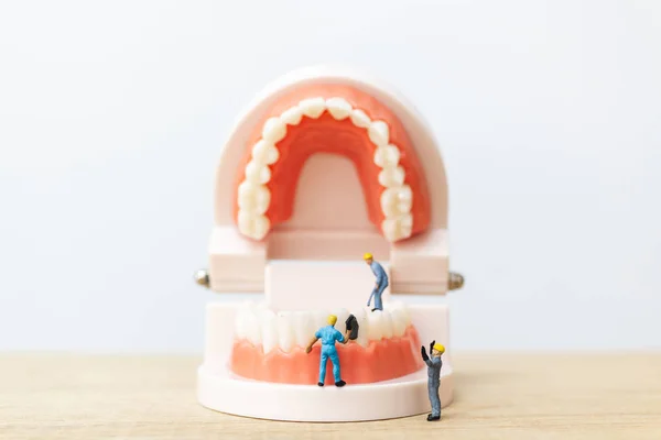 Miniaturmenschen: Arbeiterteam repariert einen Zahn — Stockfoto