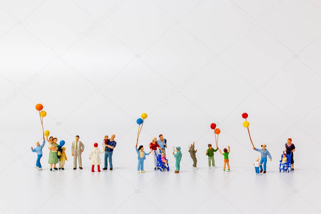 Miniature people holding balloon isolated on white background 