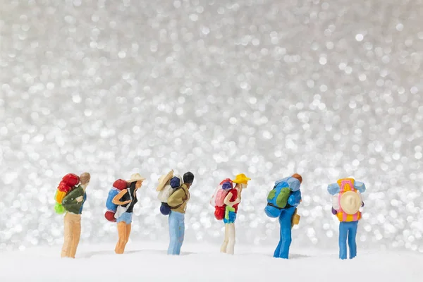 Miniaturní lidé: batůžkářský pěší turistika na sněhu — Stock fotografie