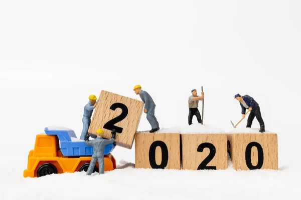 Miniature people : Worker team create wooden block number 2020
