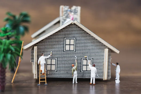 Miniature people: Workers team painting a new home.