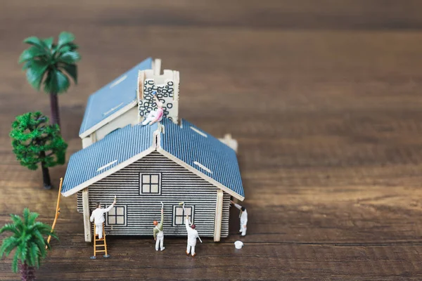 Miniature people: Workers team painting a new home.