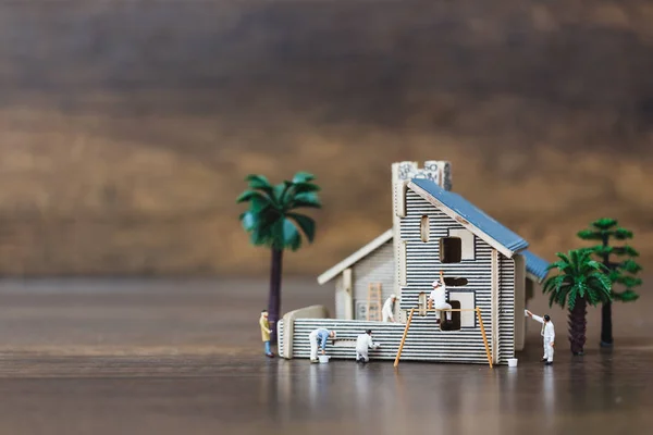 Miniature people: Workers team painting a new home.