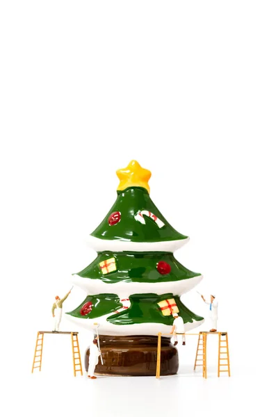 Miniature worker team painting Christmas prop on white background