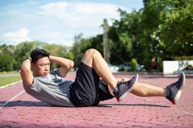 Güç ve motivasyon. Spor kıyafetli genç Asyalı parkta şınav çekiyor.