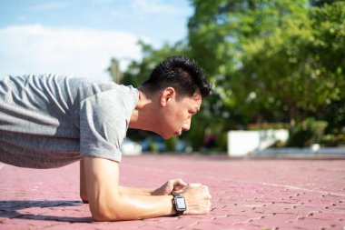 Güç ve motivasyon. Spor kıyafetli genç Asyalı parkta şınav çekiyor.