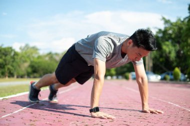Güç ve motivasyon. Spor kıyafetli genç Asyalı parkta şınav çekiyor.