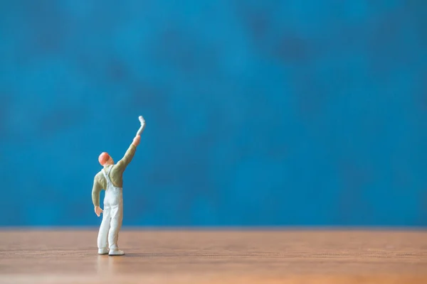 Мініатюрні Люди Тримають Пензлик Перед Фоном Синьої Стіни — стокове фото