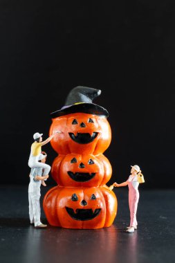 Küçük heykeltraşlar boyayıp dekore ediyorlar. Cadılar Bayramı için balkabakları istiflediler. Mutlu yüzlü balkabakları.