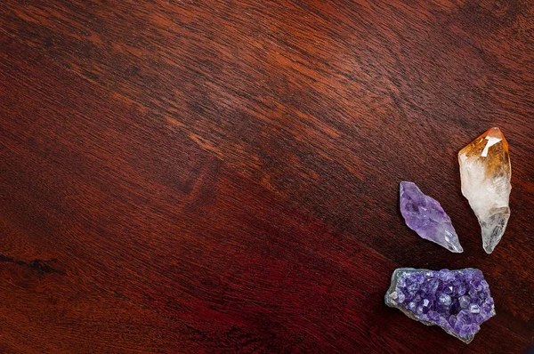 Healing crystals and gemstones: Amethysts and citrine point on a wooden table. Gemstones are used for their good vibes to bring inner strength, positive energy and inner peace