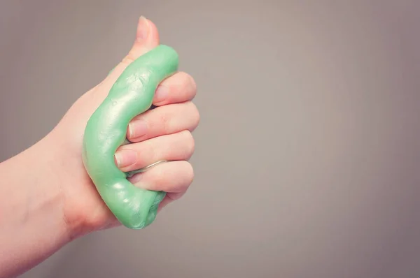 An active kid squeezing fluffy green slime: Slime is a funny toy to activate  playing kids.