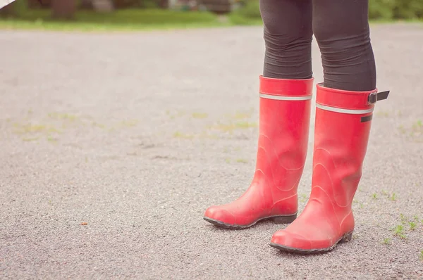 Legs below knees wearing red boots in Finnish nature. Traditional foot wear in Finland