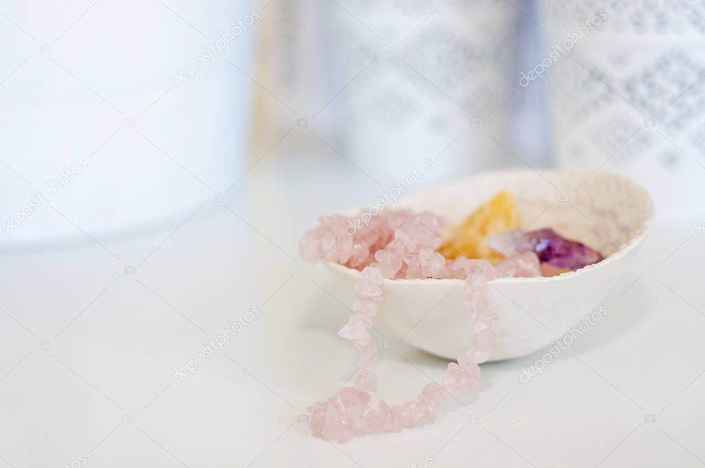Healing crystals and gemstones on a white table: Amethyst Point, Citrine, Calcite and rose quartz are bringing positive energy to support inner strength