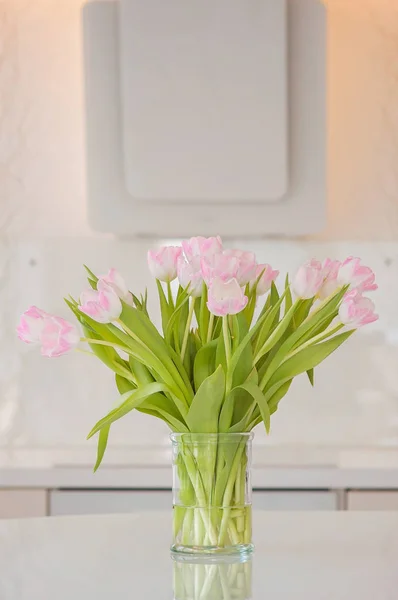 A fresh and clean home office with soft pink tulip flowers in a kitchen for Women's Day celebration. Airy Scandinavian/Nordic interior style on a media office in Finland.