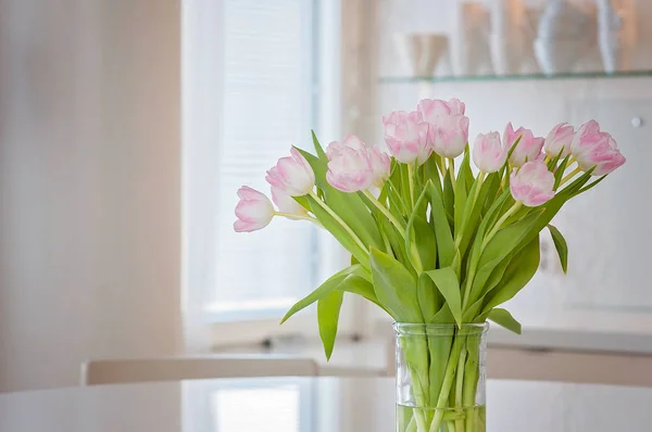A fresh and clean home office with soft pink tulip flowers in a kitchen for Women\'s Day celebration. Airy Scandinavian/Nordic interior style on a media office in Finland.