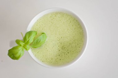 Sağlıklı yeşil çay matcha latte fesleğen ve köpük üst - beyin fonksiyonları artırmak için sıcak bir içecek ve kanserden korunma olarak süslenmiş beyaz çay bardağı soya ve yulaf sütlü!