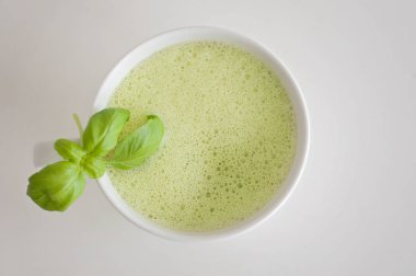 Sağlıklı yeşil çay matcha latte fesleğen ve köpük üst - beyin fonksiyonları artırmak için sıcak bir içecek ve kanserden korunma olarak süslenmiş beyaz çay bardağı soya ve yulaf sütlü!