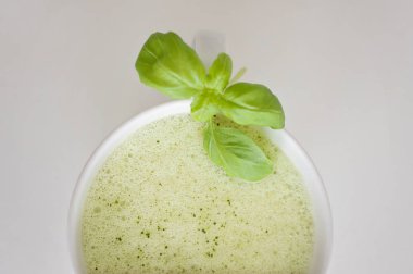 Sağlıklı yeşil çay matcha latte fesleğen ve köpük üst - beyin fonksiyonları artırmak için sıcak bir içecek ve kanserden korunma olarak süslenmiş beyaz çay bardağı soya ve yulaf sütlü!