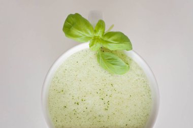 Sağlıklı yeşil çay matcha latte fesleğen ve köpük üst - beyin fonksiyonları artırmak için sıcak bir içecek ve kanserden korunma olarak süslenmiş beyaz çay bardağı soya ve yulaf sütlü!