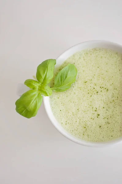 Υγιή πράσινο τσάι latte matcha με σόγια και βρώμη γάλα σε ένα φλιτζάνι λευκό τσάι διακοσμημένα με βασιλικό και αφρό στην κορυφή - ένα ζεστό ρόφημα να ενισχύσει τη λειτουργία του εγκεφάλου και ως πρόληψη του καρκίνου! — Φωτογραφία Αρχείου
